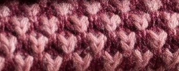 Close-up of a dusty-pink honeycomb knit: raised diamonds, darker hollows.