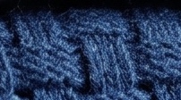 Close-up of a navy basketweave knit: staggered horizontal floats, tight gauge.