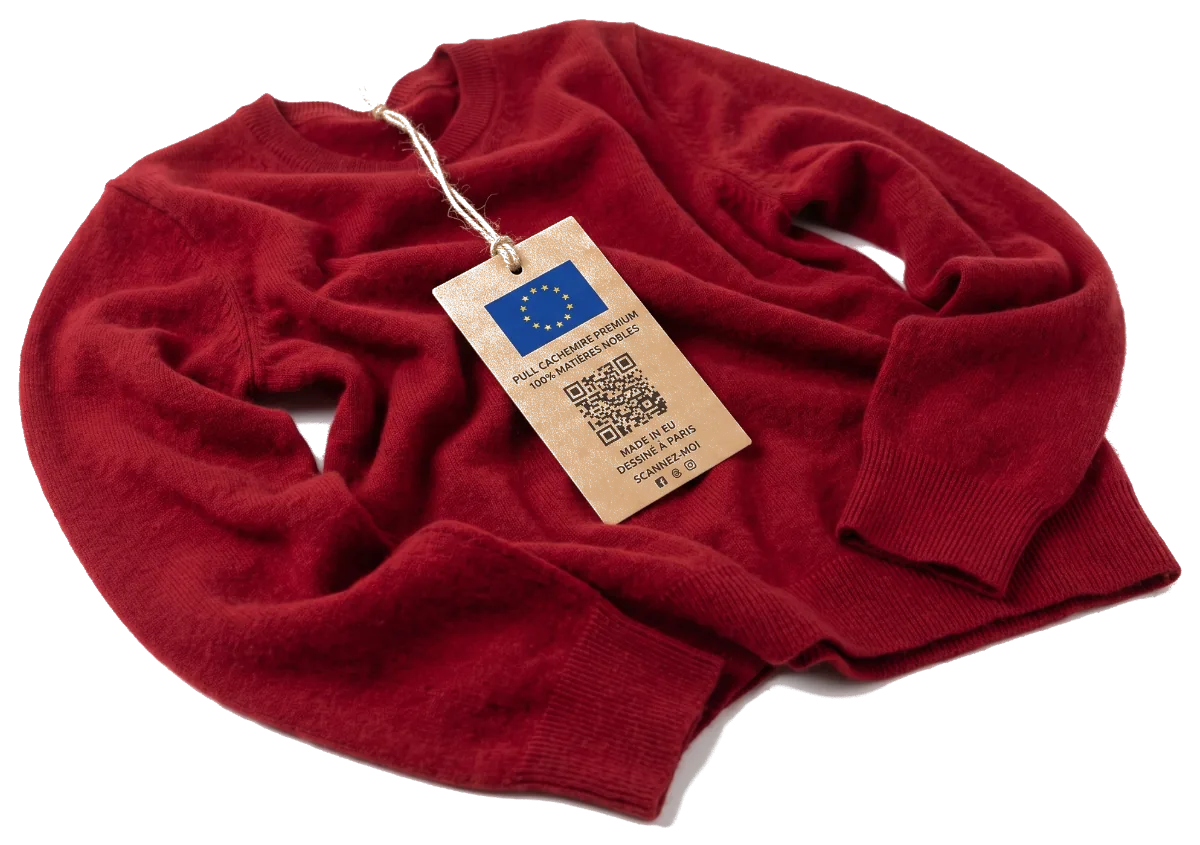 A red cashmere sweater laid flat, with a kraft card tag hanging from a string: European flag, the wording “premium cashmere sweater, 100% fine materials”, a QR code and the place of manufacture.